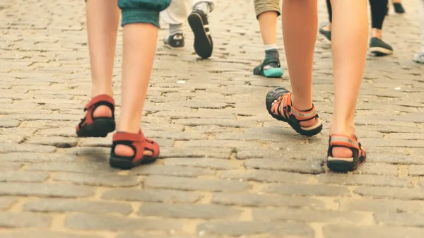 Niños con pantalones cortos y sandalias caminan sobre pavimento de adoquines —  Fotos de Stock