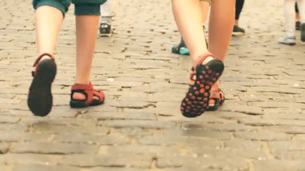 Niños con pantalones cortos y sandalias caminan sobre pavimento de adoquines — Vídeo de stock