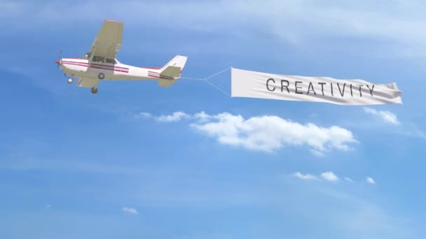 Kleines Propellerflugzeug schleppt Banner mit Kreativität Bildunterschrift in den Himmel. 4k-Clip — Stockvideo