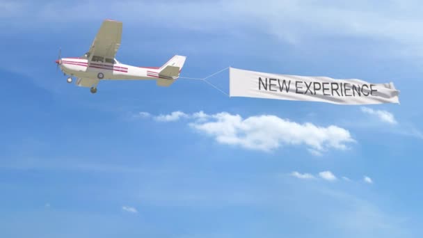 Small propeller airplane towing banner with NEW EXPERIENCE caption in the sky. 4K clip — Stock Video