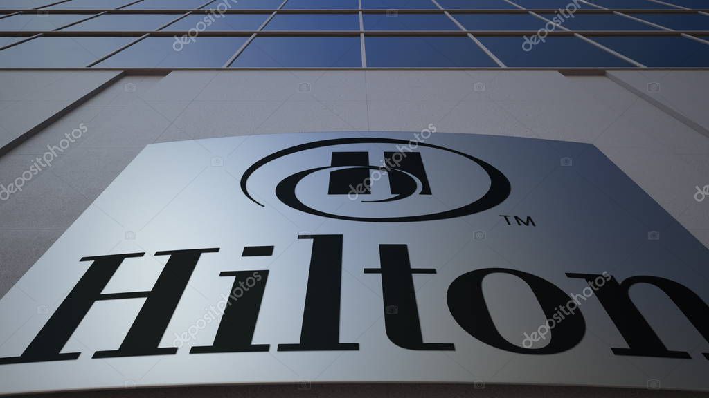 Outdoor signage board with Hilton Hotels Resorts logo. Modern office building. Editorial 3D
