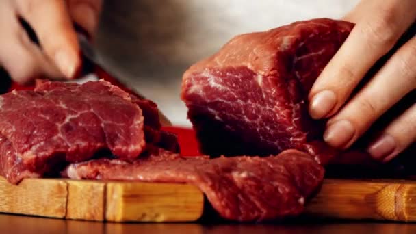 Young woman cuts raw red meat on the wooden cutting board. 4K close-up shot — Stock Video