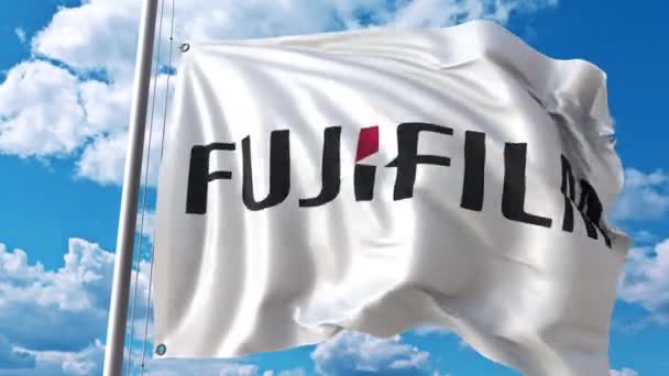 Bandera ondeante con logotipo de Fujifilm contra nubes móviles. Animación editorial 4K — Vídeo de stock