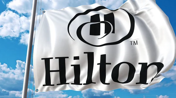 Bandera ondeando con el logotipo de Hilton contra el cielo y las nubes. Representación Editorial 3D — Foto de Stock