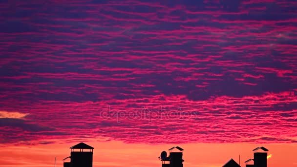 Lindas nuvens cor-de-rosa se movem sobre os telhados da cidade. 4K lapso de tempo da noite — Vídeo de Stock