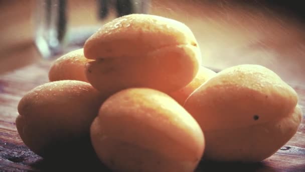 Het sproeien van water over rijp verse abrikozen op een houten tafel. Close-up slow-motion shot — Stockvideo