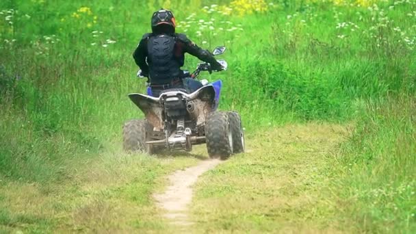 Unknown man wearing protective suit riding ATV or quad on a dusty outskirts road. Slow motion shot — Stock Video