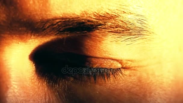 Jonge man opent en sluit zijn groene ogen. 4 k close-up shot, warme zonsondergang kleuren — Stockvideo