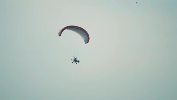 Unbekannter fliegt Gleitschirm gegen blauen Himmel — Stockvideo