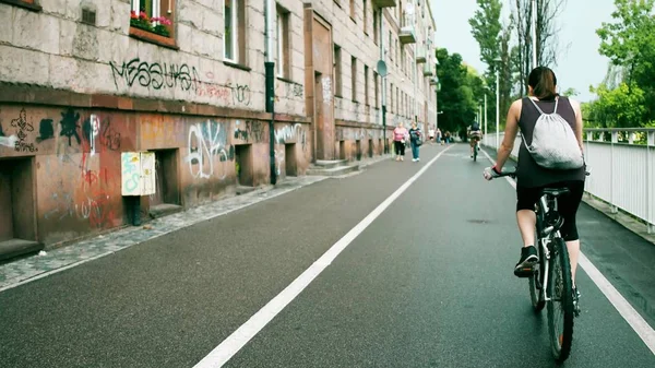 Невідома молода жінка зі спиною їде на велосипеді вздовж міської велосипедної доріжки — стокове фото