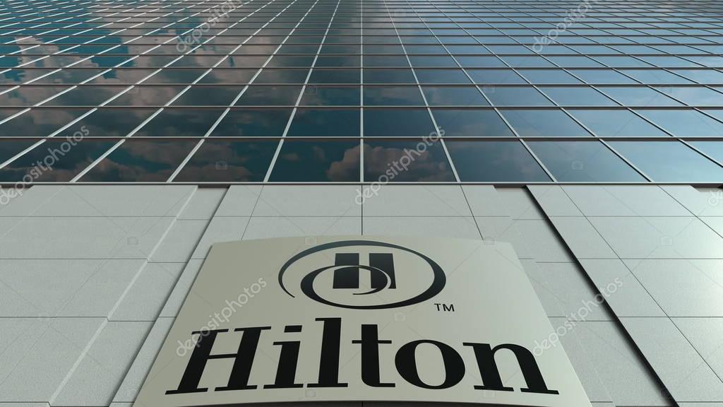 Outdoor signage board with Hilton Hotels Resorts logo. Modern office building. Editorial 3D