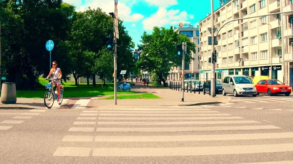 WARSAW, POLONIA - 11 de julio de 2017. Joven mujer ciclismo a lo largo de la calle de la ciudad crosswalk — Foto de Stock