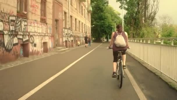 ワルシャワ, ポーランド - 2017 年 7 月 11 日。都市の自転車道路に沿って彼女の自転車に乗って backsack を持つ若い女性 — ストック動画