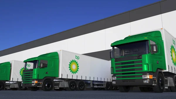 Semi-caminhões de carga com logotipo da BP carregando ou descarregando na doca do armazém. Renderização 3D editorial — Fotografia de Stock