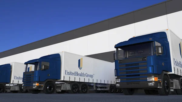 Frakt semi lastbilar med Unitedhealth grupplogotyp lastning eller lossning på lager dock. Redaktionella 3d-rendering — Stockfoto