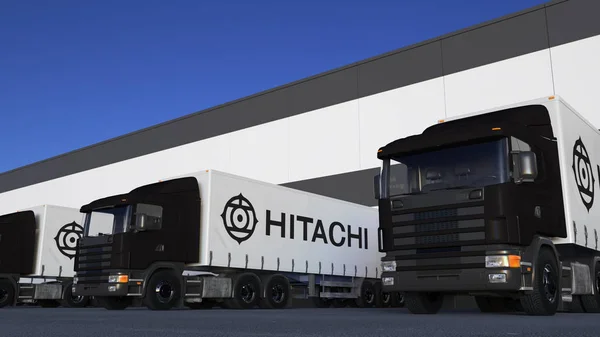Грузовые полугрузовики с логотипом Hitachi погрузки или разгрузки на складе док. Редакционная 3D рендеринг — стоковое фото