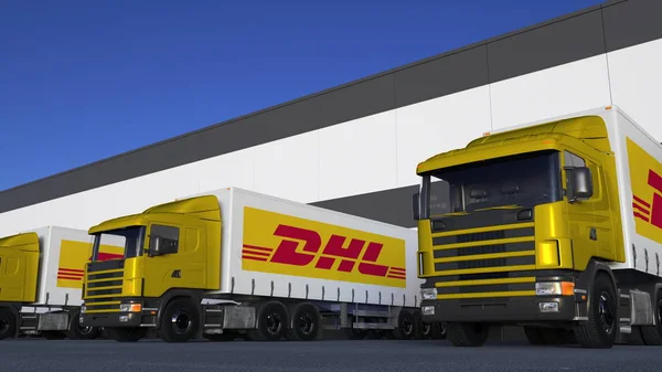 Грузовые полугрузовики с логотипом DHL Express погрузки или разгрузки на складе док. Редакционная 3D рендеринг — стоковое фото