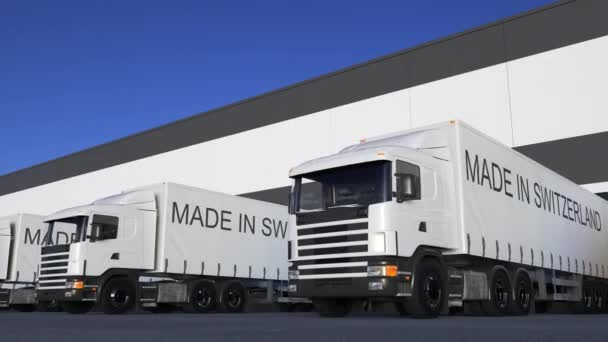 Frakt semi lastbilar med gjort i Schweiz bildtext på släpet lastning eller lossning. Road cargo transport. Sömlös loop 4k klipp — Stockvideo