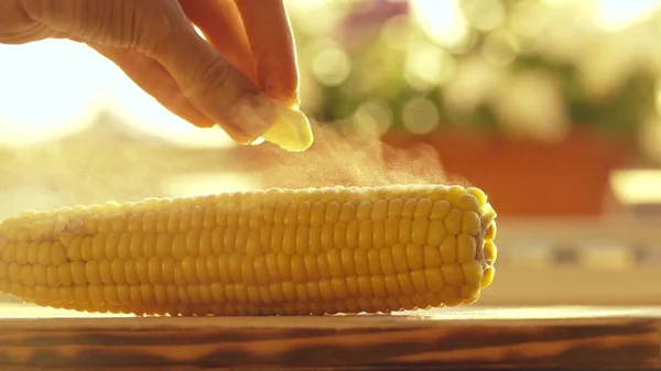 Mano femenina colocando un trozo de mantequilla sobre maíz recién hervido caliente — Foto de Stock