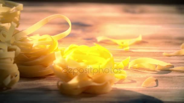 Tagliatelle de pasta italiana tradicional sin cocer sobre una mesa de madera — Vídeos de Stock