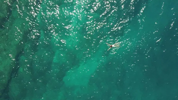 Vue aérienne du haut vers le bas d'une fille en maillot de bain blanc nageant dans la mer — Photo