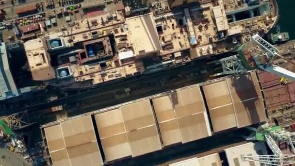 Aerial top down view of a shipyard, cranes and unfinished ship — Stock Video