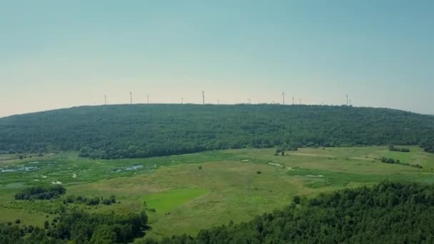 Вид с воздуха на несколько ветрогенераторов над лесом. Концепция производства зеленой энергии — стоковое видео
