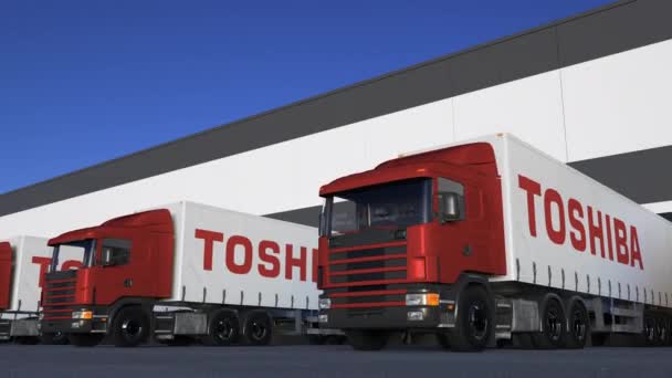 Semi-camions de fret avec logo Toshiba Corporation chargement ou déchargement au quai de l'entrepôt, boucle transparente. Éditorial animation 4K — Video