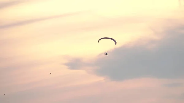 Неизвестный параплан, летящий высоко в небе на закате — стоковое фото