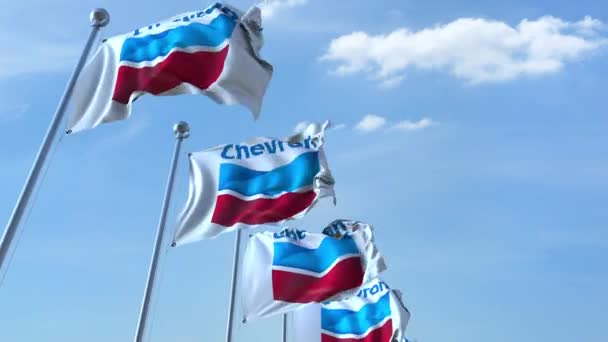 Waving flags with Chevron logo against sky, seamless loop. 4K editorial animation — Stock Video