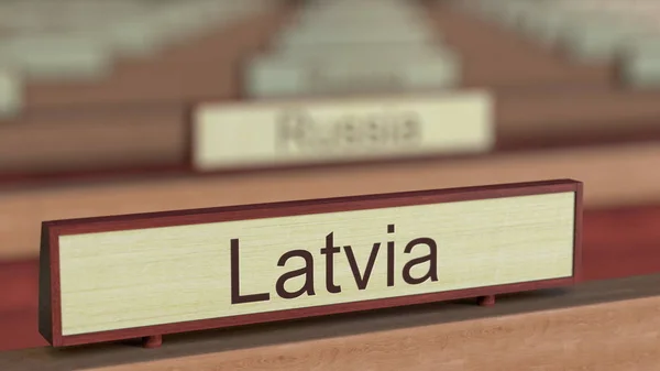 Латвія ім'я знак серед різних країн бляшок на міжнародної організації. 3D-рендерінг — стокове фото