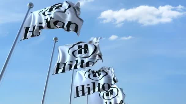 Bandiere sventolanti con logo Hilton contro il cielo, anello senza cuciture. Animazione editoriale 4K — Video Stock