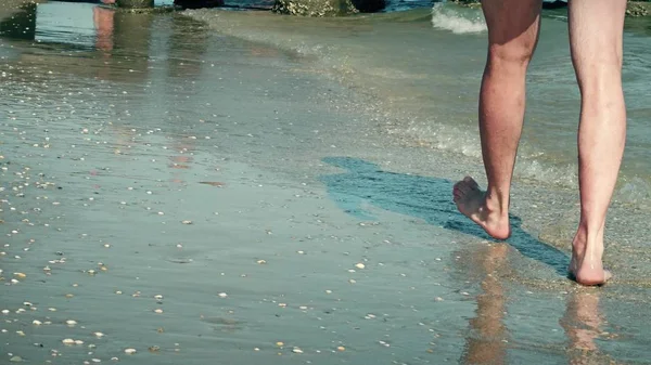 Jambes d'un homme marchant le long de la mer — Photo