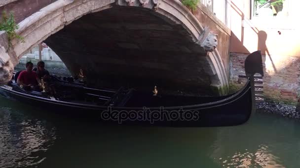 Venice, Italië - 8 augustus 2017. Venetiaanse gondel met toeristen passeren onder de brug — Stockvideo