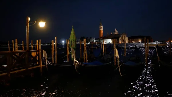 Moored gondolas in Venice at night and distant San Giorgio Maggiore island — Stock Photo, Image