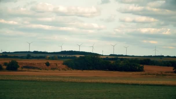 Avlägsna snurrande vindkraftverk och fältet i Österrike sett från flyttar bilen — Stockvideo