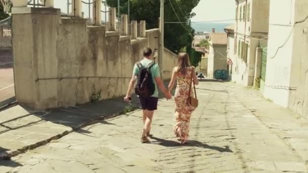 Pareja joven caminando hacia el mar en una ciudad mediterránea — Vídeo de stock