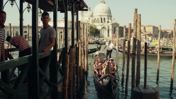 Benátky, Itálie - 8 srpna 2017. Pohyblivé gondoly s turisty poblíž San Marco čtvercová proti Santa Maria della Salute římsko-katolické církve — Stock video