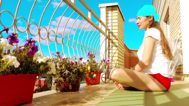 Mooie jongedame ontspannen op het balkon na fitness of yoga — Stockvideo
