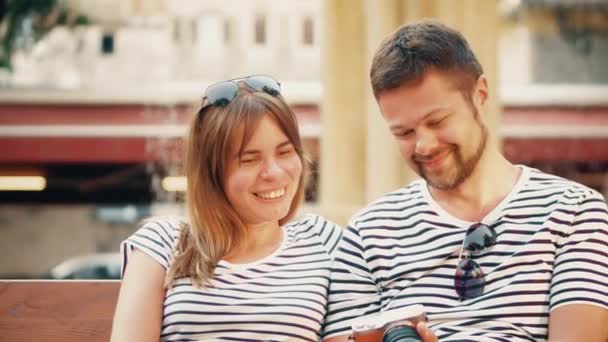 Молодая счастливая пара смотрит фотографии в фотоаппарате во время отпуска — стоковое видео
