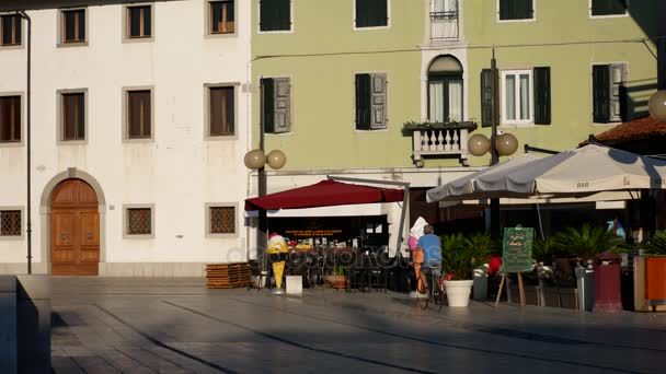 Palmanova, Włochy - 11 sierpnia 2017 r. Mężczyzna jazdy na rowerze w pobliżu kawiarni ulicznych i starych budynków — Wideo stockowe