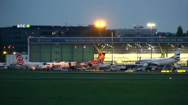 Βαρσοβία, Πολωνία - 14 Σεπτεμβρίου 2017. Εμπορικά αεροπλάνα και οχήματα κοινής ωφέλειας στο Διεθνές Αεροδρόμιο Chopin της τερματικού τη νύχτα — Φωτογραφία Αρχείου