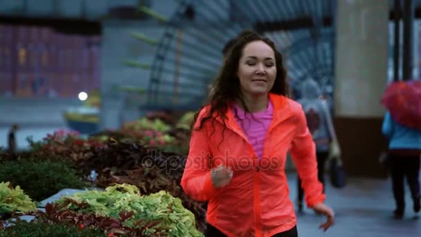 Joven mujer atlética de raza mixta comienza a correr a lo largo del terraplén del parque de la ciudad por la noche, disparo en cámara lenta — Vídeos de Stock