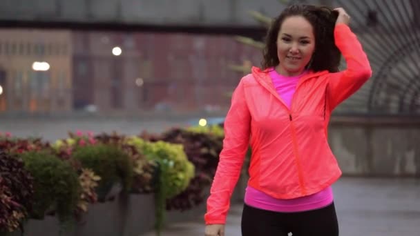 Alegre mujer de raza mixta comienza a correr a lo largo del terraplén del parque de la ciudad en la noche, cámara lenta — Vídeos de Stock