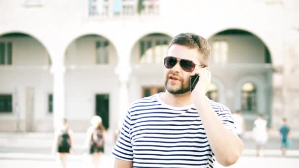 Красивый мужчина разговаривает по мобильному телефону на улице — стоковое видео