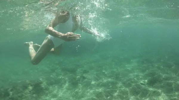 Plan sous-marin d'une belle jeune femme en maillot de bain blanc nageant dans la mer — Photo