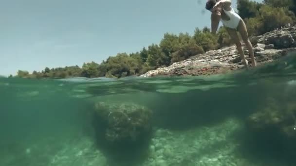 Тонкая молодая женщина ныряет в море, под водой выстрел — стоковое видео