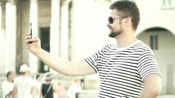 Веселый бородатый мужчина делает селфи с телефоном в отпуске — стоковое видео