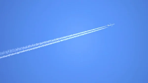 Motor avgaser kondensstrimmor bildas bakom flygande kommersiella flygplan — Stockfoto