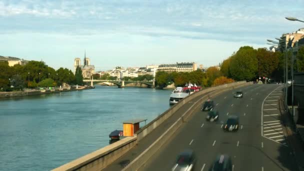 Caducidad del tráfico de automóviles en el dique del río Sena en París y la lejana Catedral de Notre-Dame, Francia — Vídeo de stock